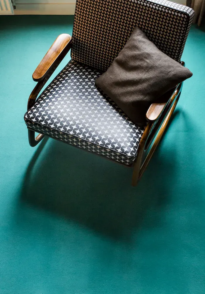 Carpet Dark Basalt under a curved timber armchair