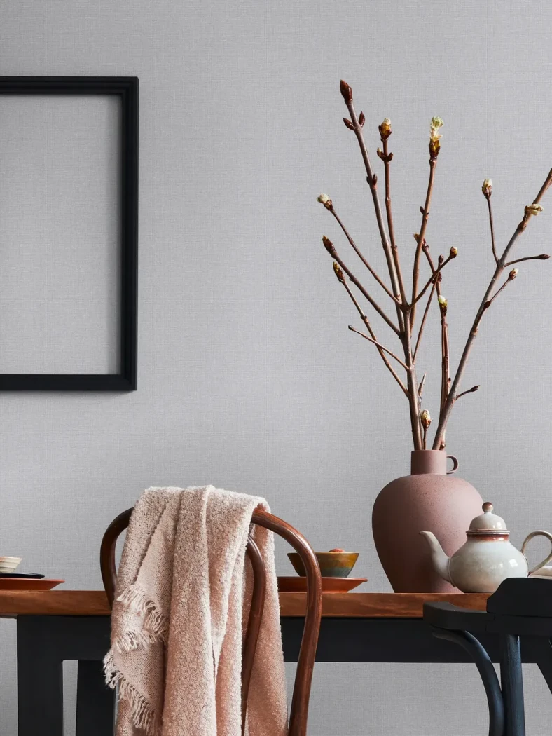 Wallpaper Veiled Steel, linen-effect grey wall behind a dark wood table