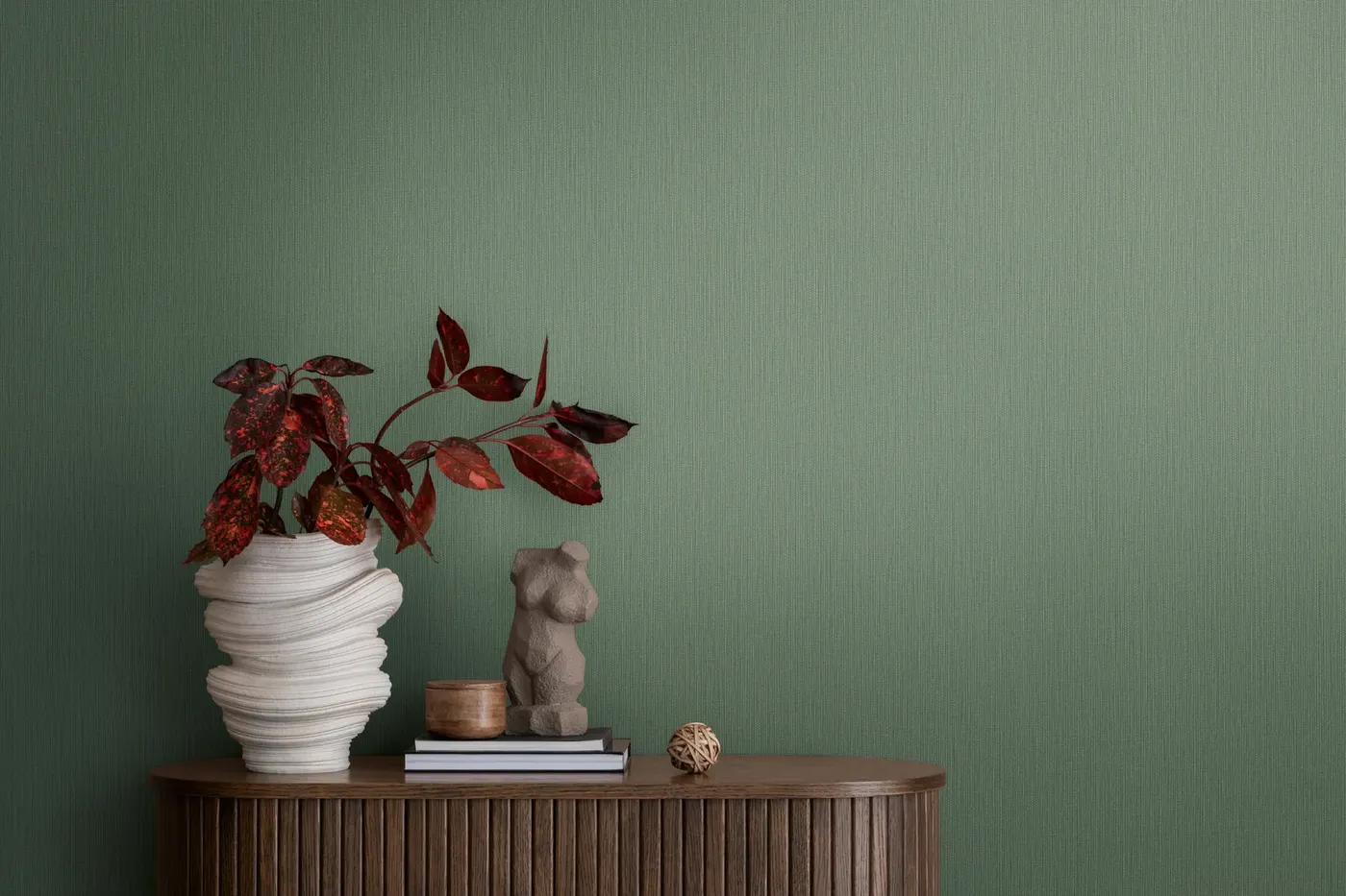 Wallpaper Soft Absinthe, plain sage green wall behind a wooden sideboard